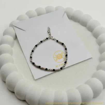 Experience the perfect fusion of celestial sparkle and traditional protection with the KJJ Radiant Star-Cut Bracelet. This standout piece features a stunning sequence of 3mm imported silver balls with a unique star-cut (diamond-cut) texture, designed to catch and reflect light with maximum brilliance. Alternated with sleek black beads, this bracelet is a sophisticated modern take on the classic "Nazar Battu". Crafted from certified 92.5 Sterling Silver, this bracelet features a premium metallic build that swaps the traditional thread for a more formal and secure silver chain finish. It is the ideal accessory for the woman who wants her protective jewelry to shine with high-end, jewelry-store quality. Key Highlights: 92.5 Sterling Silver Purity: Guaranteed high-quality silver components, including the star-cut beads, chain, and clasp, for a long-lasting and skin-friendly finish. 3mm Star-Cut Imported Beads: Features a precision faceted texture that provides significantly more sparkle than standard smooth silver balls. Secure Adjustable Lock: Equipped with a durable lobster claw clasp and extension chain, allowing for a perfect, secure fit on any wrist size. Premium Metal Construction: Unlike thread-based designs, this bracelet offers a more formal, high-end feel suitable for both daily wear and special occasions. Modern Symbolic Style: Beautifully balances the spiritual significance of black protective beads with the luxurious radiance of diamond-cut silver. Product Specifications: Brand: Kanhaji Jewels (KJJ) Material: 92.5 Sterling Silver & Premium Black Beads Silver Bead Texture: 3mm Star-Cut / Diamond-Cut (Imported) Closure Type: Adjustable Lobster Claw with Extension Chain Quantity: 1 Piece