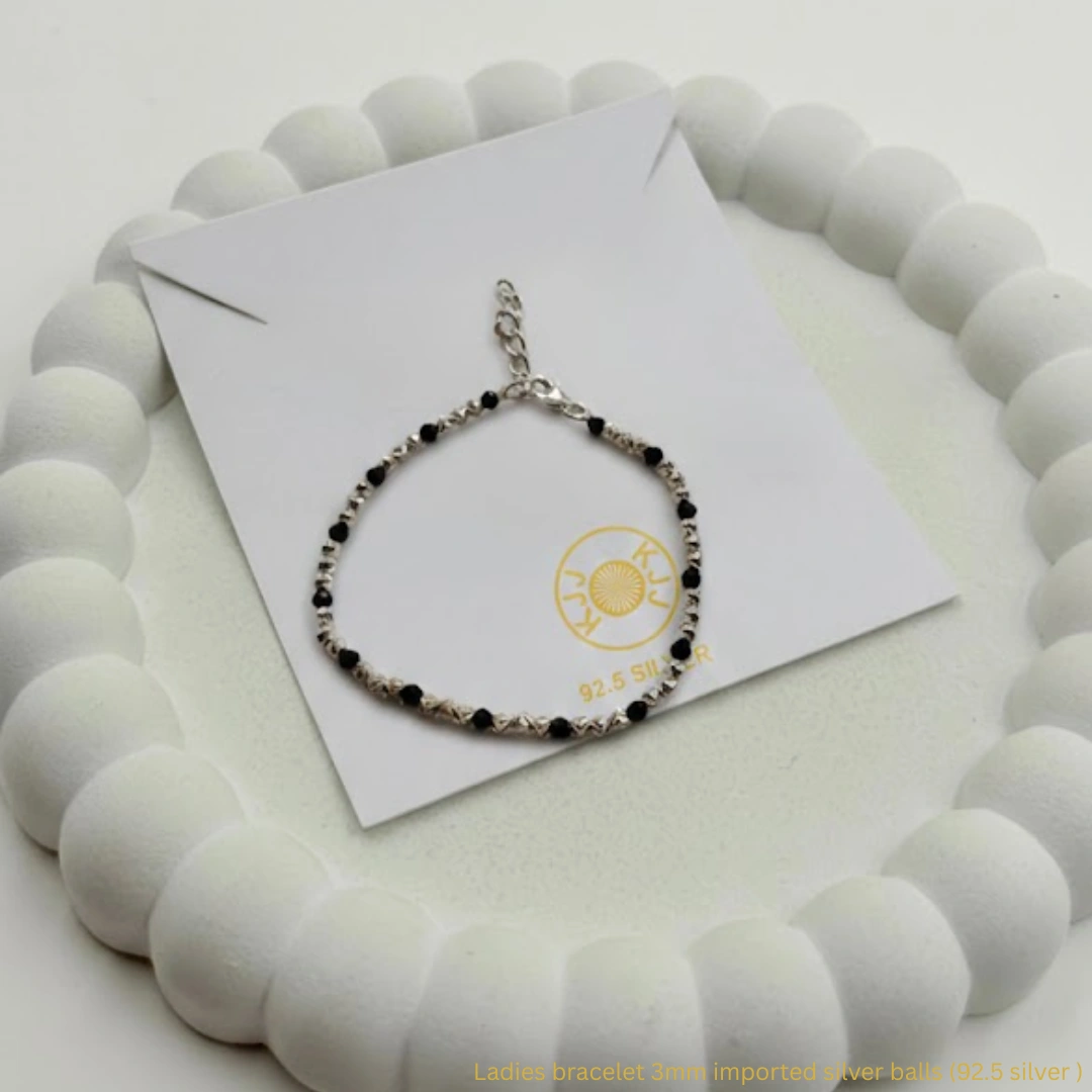 Experience the perfect fusion of celestial sparkle and traditional protection with the KJJ Radiant Star-Cut Bracelet. This standout piece features a stunning sequence of 3mm imported silver balls with a unique star-cut (diamond-cut) texture, designed to catch and reflect light with maximum brilliance. Alternated with sleek black beads, this bracelet is a sophisticated modern take on the classic "Nazar Battu". Crafted from certified 92.5 Sterling Silver, this bracelet features a premium metallic build that swaps the traditional thread for a more formal and secure silver chain finish. It is the ideal accessory for the woman who wants her protective jewelry to shine with high-end, jewelry-store quality. Key Highlights: 92.5 Sterling Silver Purity: Guaranteed high-quality silver components, including the star-cut beads, chain, and clasp, for a long-lasting and skin-friendly finish. 3mm Star-Cut Imported Beads: Features a precision faceted texture that provides significantly more sparkle than standard smooth silver balls. Secure Adjustable Lock: Equipped with a durable lobster claw clasp and extension chain, allowing for a perfect, secure fit on any wrist size. Premium Metal Construction: Unlike thread-based designs, this bracelet offers a more formal, high-end feel suitable for both daily wear and special occasions. Modern Symbolic Style: Beautifully balances the spiritual significance of black protective beads with the luxurious radiance of diamond-cut silver. Product Specifications: Brand: Kanhaji Jewels (KJJ) Material: 92.5 Sterling Silver & Premium Black Beads Silver Bead Texture: 3mm Star-Cut / Diamond-Cut (Imported) Closure Type: Adjustable Lobster Claw with Extension Chain Quantity: 1 Piece