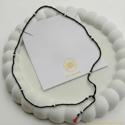 Simple Protection, Pure Tradition. Adorn your little one with the KJJ Essential Baby Kamarband, a piece that beautifully balances minimalist design with sacred tradition. This waist chain is handcrafted for daily wear, featuring delicate 92.5 Sterling Silver accents interspersed along a durable, skin-friendly black thread. Designed to be the perfect first "Kamarband" (waist belt) for newborns and infants, it serves as a subtle yet powerful "Nazar Battu". The lightweight construction ensures your baby remains comfortable all day long, while the pure silver elements provide a touch of timeless luxury that stays close to their skin. Key Highlights: 92.5 Sterling Silver Purity: Features multiple high-purity silver accents that are hypoallergenic and safe for sensitive infant skin. Minimalist "Nazar Battu" Design: Uses the traditional black thread and silver combination to ward off negative energy without being bulky. Soft & Lightweight Cord: Hand-strung on a premium black thread that is soft enough for newborns and strong enough for active toddlers. Adjustable Tassel Closure: Finished with a signature red and black tassel, allowing you to easily adjust the length for a perfect, secure fit as your baby grows. Everyday Spiritual Wear: Its subtle profile makes it ideal for wearing under clothing or as a standalone accessory for daily protection. Product Specifications: Brand: Kanhaji Jewels (KJJ) Material: 92.5 Sterling Silver & High-Grade Black Thread Category: Baby Jewelry / Kamarband (Waist Chain) Quantity: 1 Piece