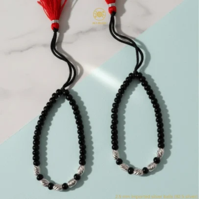 Celestial Brilliance for Your Little Star. Give your baby a touch of high-end sparkle with the KJJ Radiant Baby Nazariya. This exquisite set features premium 2.5mm imported silver balls with a unique star-cut (diamond-cut) texture, designed to catch and reflect light from every angle. These faceted silver beads provide a brilliant, jewel-like shine that elevates the traditional protective "Kala Dhaga" into a sophisticated piece of fine infant jewelry. Handcrafted with certified 92.5 Sterling Silver, these bracelets are meticulously hand-strung on a soft, durable black cord with polished black beads to ward off negative energy. Designed specifically for delicate infant skin, this set ensures your baby stays protected with the highest quality materials and a stunning, modern radiance. Key Highlights: Unique Star-Cut Texture: Features premium 2.5mm imported silver balls with a precision-faceted surface that offers significantly more sparkle than standard smooth beads. 92.5% Sterling Purity: Every silver component is guaranteed certified high-purity silver, ensuring it is hypoallergenic, lead-free, and safe for newborns. Sacred Nazar Protection: Combines the spiritual significance of black protective beads with pure silver to shield your child from the "evil eye". Artisan Tassel Finish: Finished with our signature red and black tassel, adding a traditional touch while providing a secure, adjustable fit as your baby grows. A Gift of Exceptional Quality: An ideal and luxurious choice for "Namkaran" (naming ceremonies), first birthdays, or a protective homecoming gift. Product Specifications: Brand: Kanhaji Jewels (KJJ) Material: 92.5 Sterling Silver & High-Grade Protective Beads Silver Ball Texture: 2.5mm Star-Cut / Diamond-Cut (Imported) Category: Infant Protection Jewelry / Nazariya Quantity: 1 Pair (Set of 2)