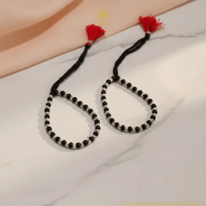 Product Description Unmatched Radiance for Your Little One's Sacred Protection. Elevate the traditional "Kala Dhaga" with the KJJ Signature High-Density Nazariya. This premium set features an increased concentration of 2.5mm imported silver balls, each meticulously engraved with an exquisite chevron (V-cut) texture. The dense arrangement of these multi-faceted silver beads creates a continuous stream of brilliance that catches the light with every tiny movement, providing a more "silver-forward" look for your infant. Handcrafted with certified 92.5 Sterling Silver, these bracelets are hand-strung on a soft, durable black cord interspersed with polished black beads to ward off negative energy. This design perfectly combines the spiritual power of a traditional "Nazar Battu" with the elegance of a luxury heirloom piece. Key Highlights: High-Density Silver Design: Features an increased number of silver beads compared to standard sets, creating a richer and more luminous aesthetic on the wrist. Chevron-Textured 2.5mm Beads: Includes premium imported silver balls with a precision-engraved texture that reflects light more brilliantly than smooth beads. Certified 92.5 Sterling Purity: Every silver component is made from guaranteed high-purity silver, ensuring it is hypoallergenic, lead-free, and safe for sensitive infant skin. Signature Tassel Finish: Finished with our iconic red and black artisan tassel, providing a traditional touch and a secure, adjustable fit for growing babies. A Luxurious Blessing: An exceptional choice for "Namkaran" (naming ceremonies), first birthdays, or as a meaningful gift from parents and grandparents. Product Specifications: Brand: Kanhaji Jewels (KJJ) Material: 92.5 Sterling Silver & High-Grade Protective Beads Silver Ball Texture: 2.5mm Chevron-Cut (Imported) Category: Infant Protection Jewelry / Nazariya Quantity: 1 Pair (Set of 2)